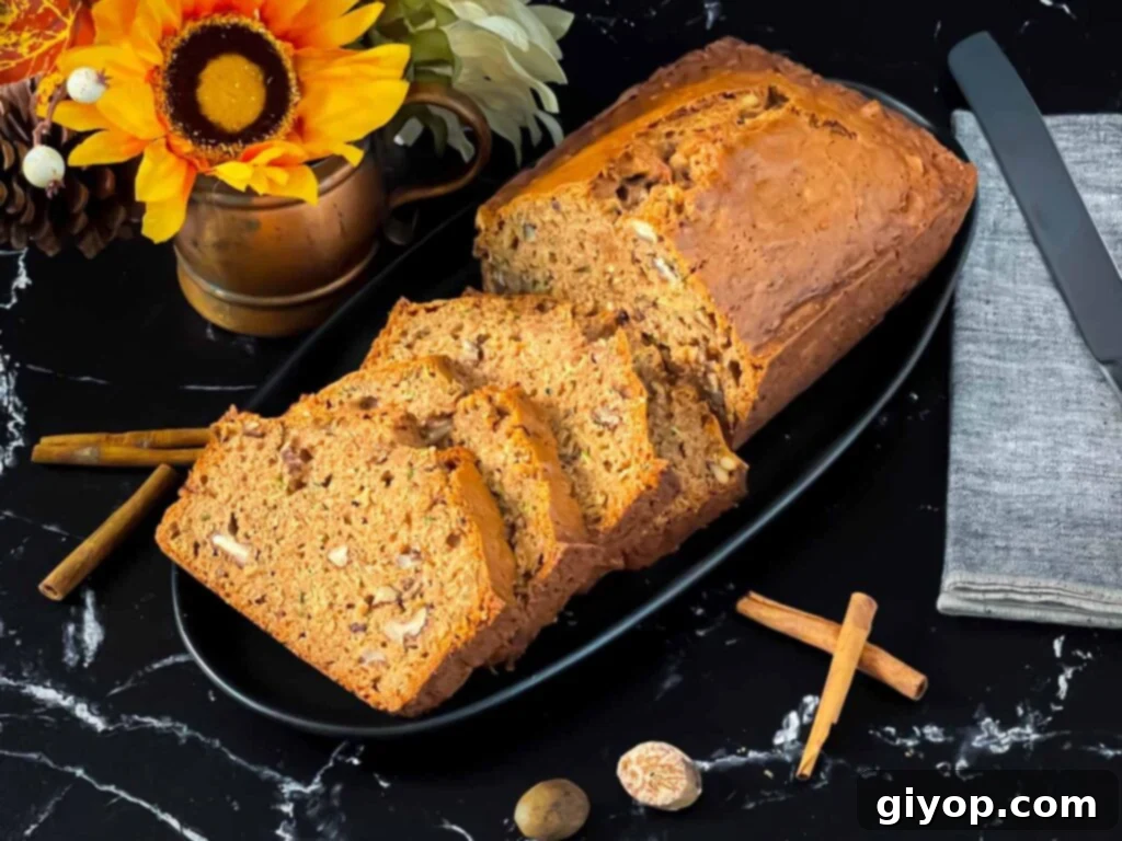 Sliced zucchini bread loaf on a dark oval platter on a dark surface.