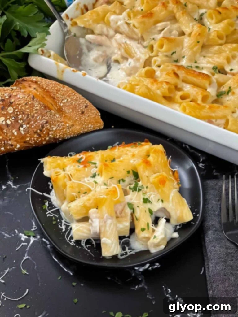 Chicken Alfredo Casserole in a white casserole dish with a serving on a black plate.