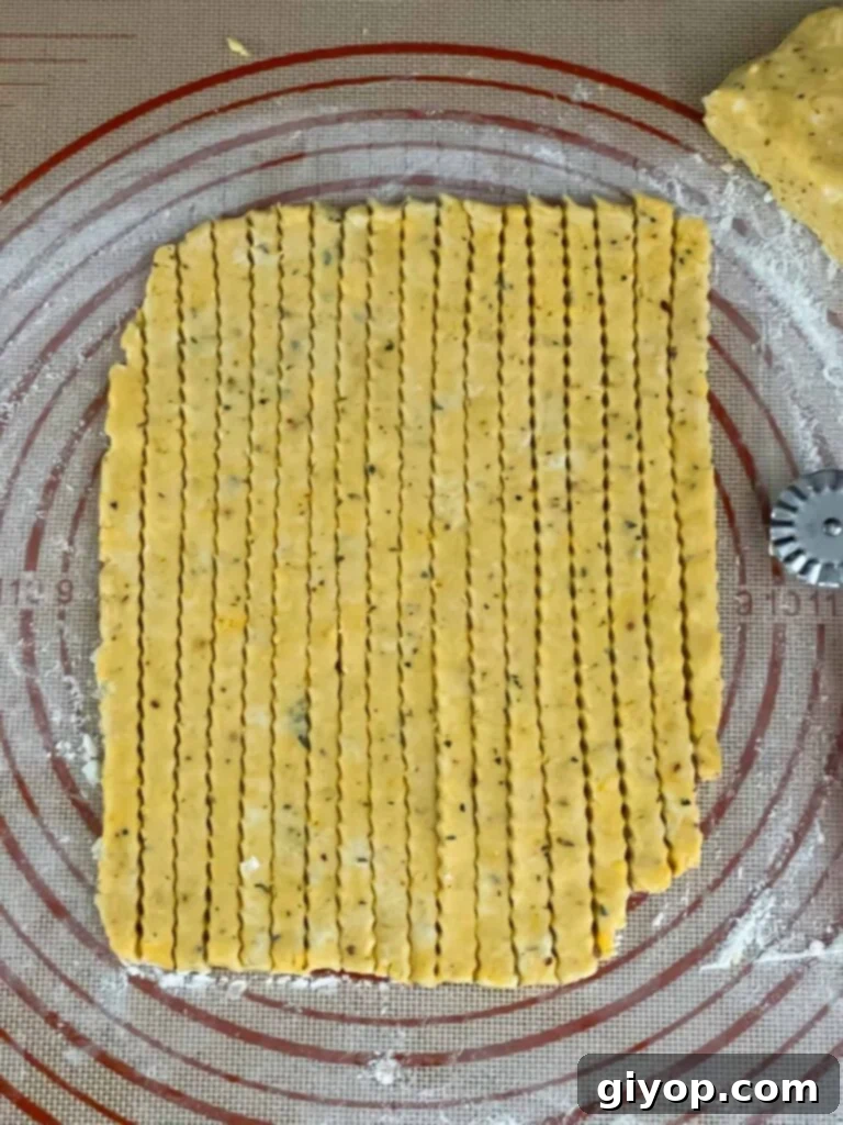 Savory Cheddar Herb Twists 11 Cheese straw dough expertly cut into thin strips and arranged on a dough mat, awaiting transfer to the baking sheet.