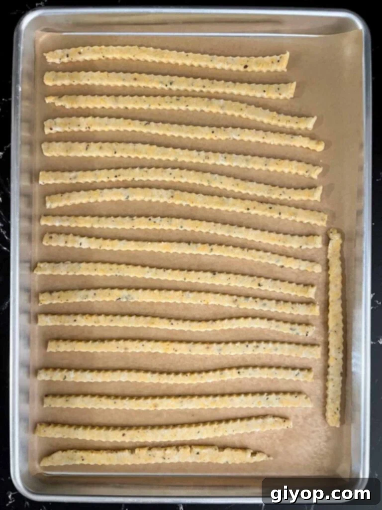 Savory Cheddar Herb Twists 12 Unbaked cheddar cheese and herb straws meticulously arranged on a parchment-lined baking sheet, ready for the oven.