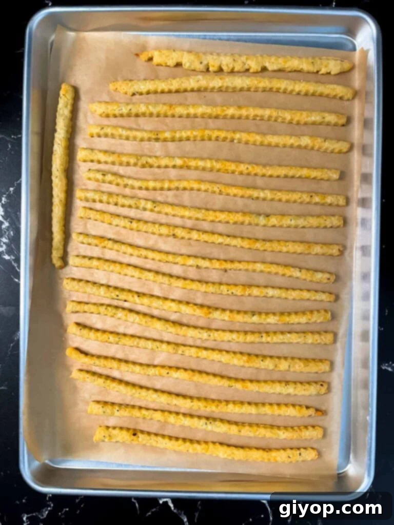 Savory Cheddar Herb Twists 13 Freshly baked cheddar cheese and herb straws cooling on a baking sheet, with a golden-brown hue and irresistible aroma.