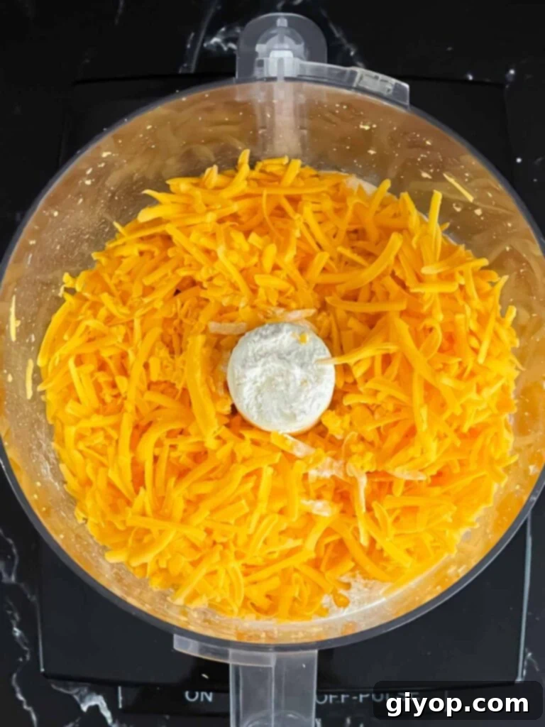 Savory Cheddar Herb Twists 4 Shredded cheddar cheese in a food processor, ready for the next step of mixing with herbs and spices.