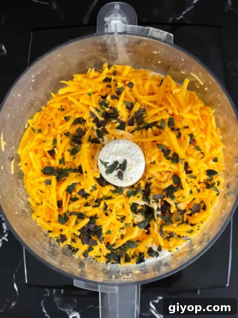 Savory Cheddar Herb Twists 5 Grated cheddar cheese, flour, and fresh herbs combined in a food processor, forming a crumbly mixture.