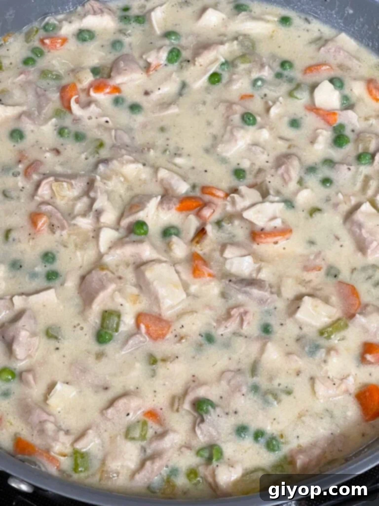 The chicken stuffing casserole mixture, fully combined in a skillet, ready for baking.