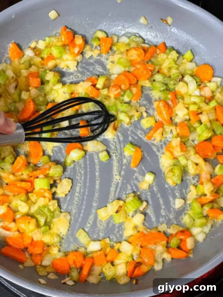 Mirepoix and roux mixture cooking in a skillet, turning golden.