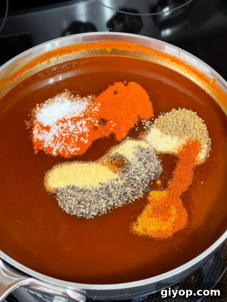 Legendary Kansas City Barbecue Sauce 5 A close-up of spices being added to the simmering base of Kansas City style barbecue sauce in a saucepan.