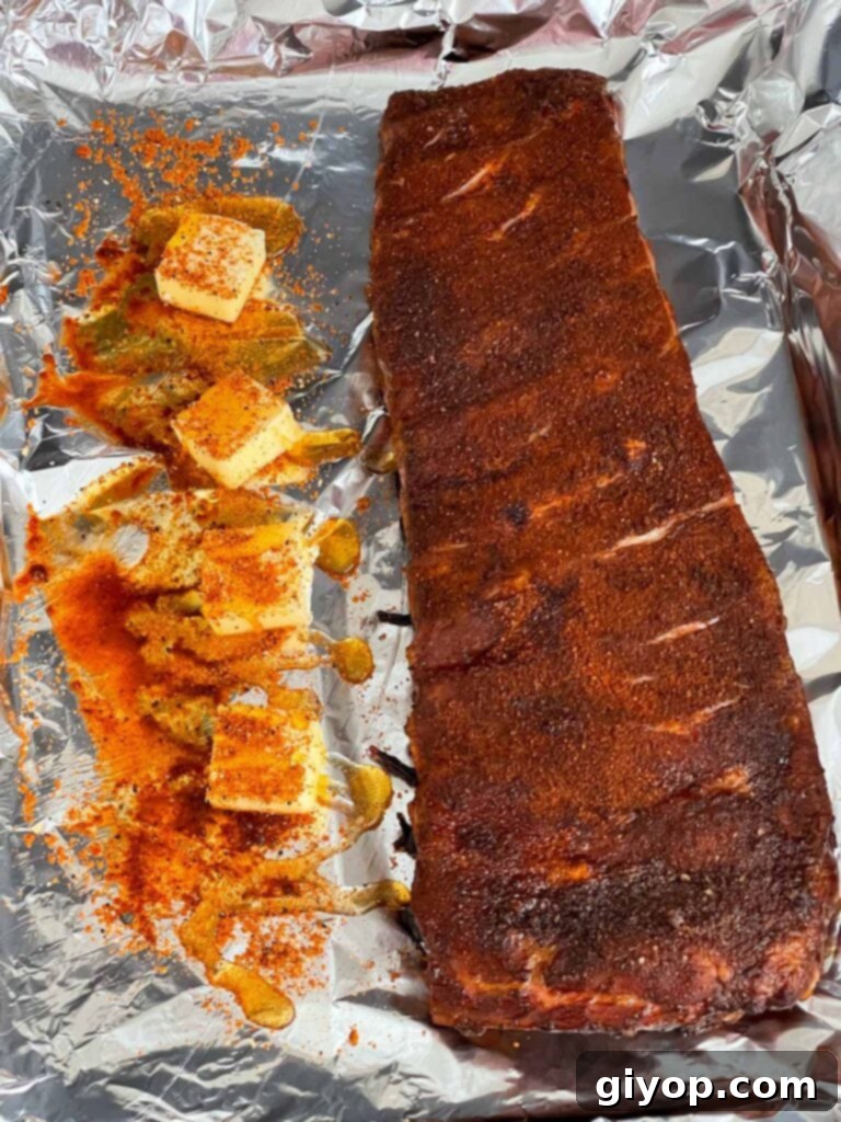 Ribs being wrapped in heavy-duty aluminum foil with butter, honey, and vinegar.
