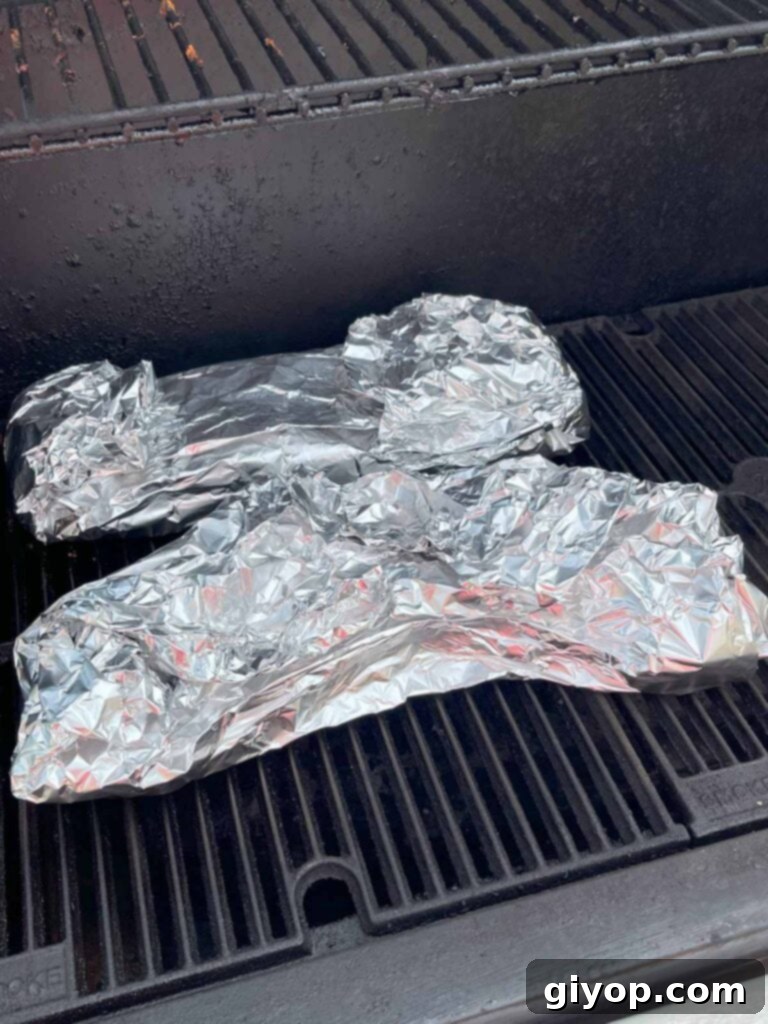 Foil-wrapped ribs placed back on the smoker to continue cooking.