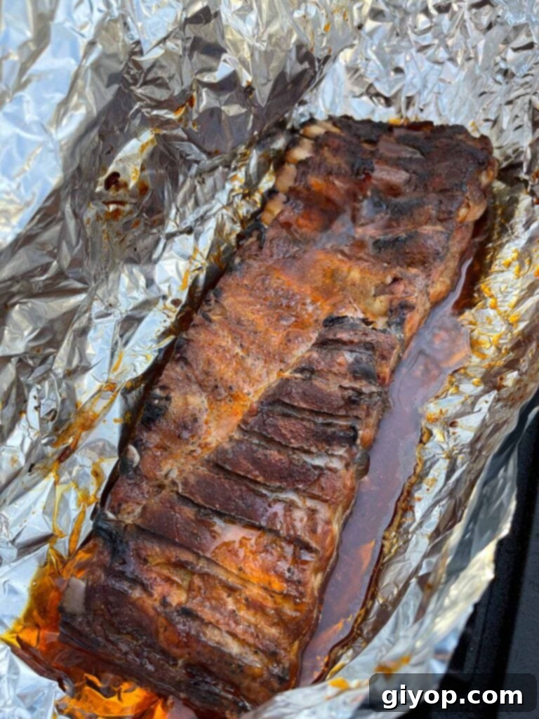 Foil-wrapped ribs just opened, revealing tender, succulent meat.