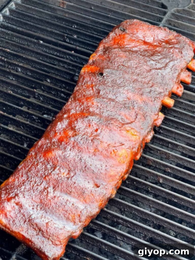 A rack of Kansas City style ribs on the smoker, with a perfect, glossy sauce.