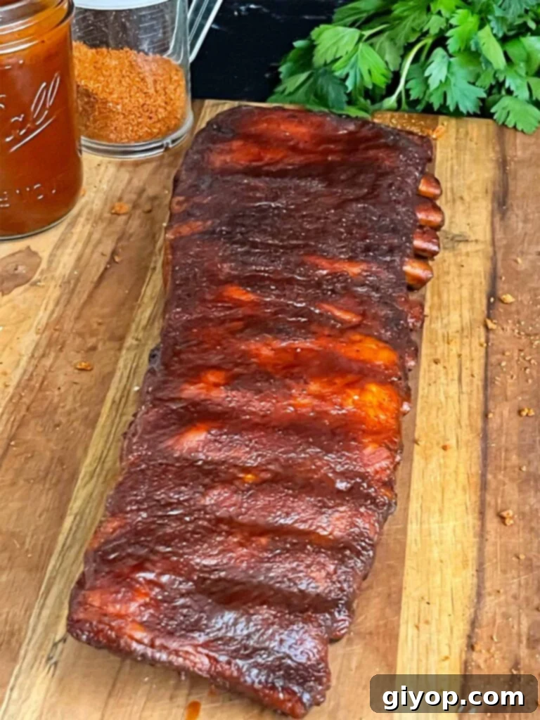 Finished Kansas City style ribs on a wooden cutting board, glistening with sauce.
