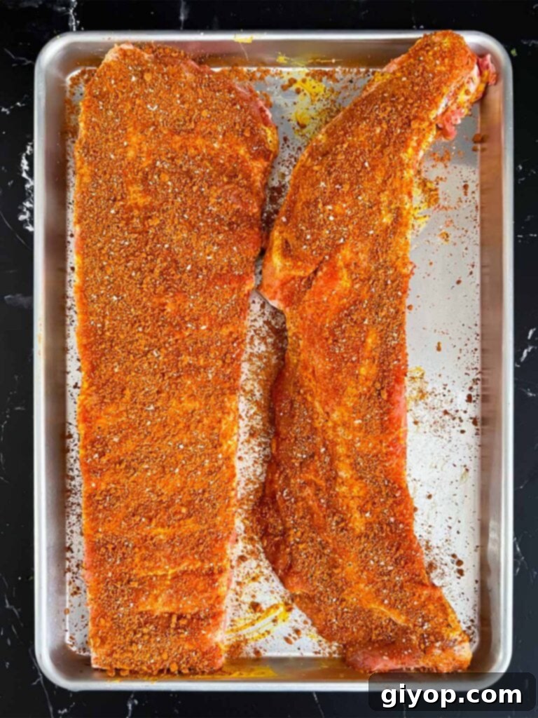 Ribs generously coated with a savory rub, ready for refrigeration.