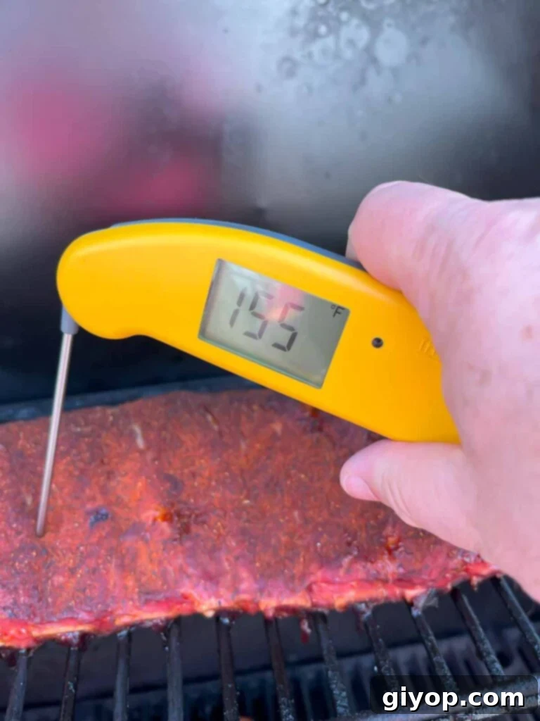 A thermometer checking the internal temperature of ribs on the smoker.