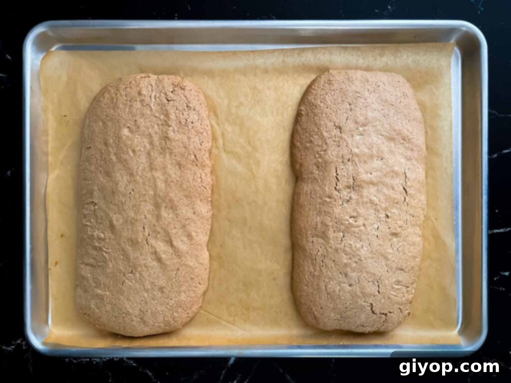 Baked chai biscotti loaves on a baking sheet, golden and ready for slicing.