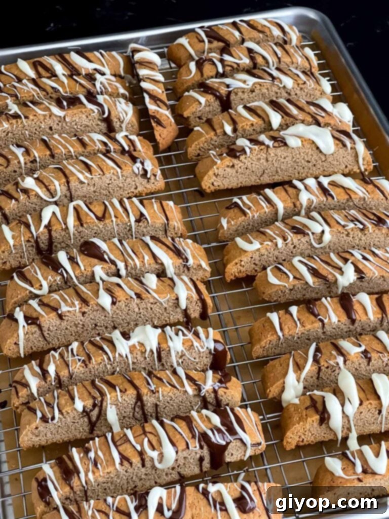 Chai biscotti with a chocolate drizzle cooling on a wire rack.