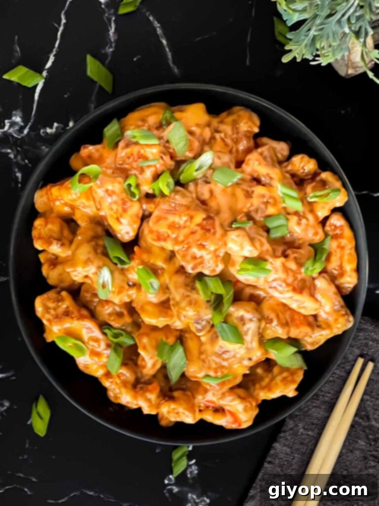 Another close-up shot of Bang Bang Chicken in a dark bowl, highlighting the crispy texture and the fresh green onion garnish.