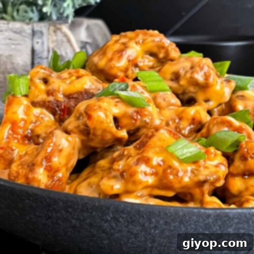 Bang Bang Chicken in a dark bowl, garnished with green onion.