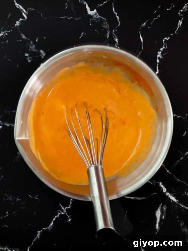 The fully mixed, creamy Bang Bang Sauce in a glass bowl, showcasing its smooth texture and light orange hue.