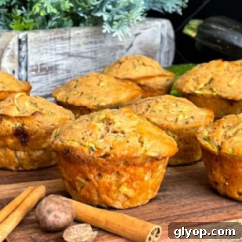Zucchini muffins on a cutting board with some cinnamon sticks and nutmeg.