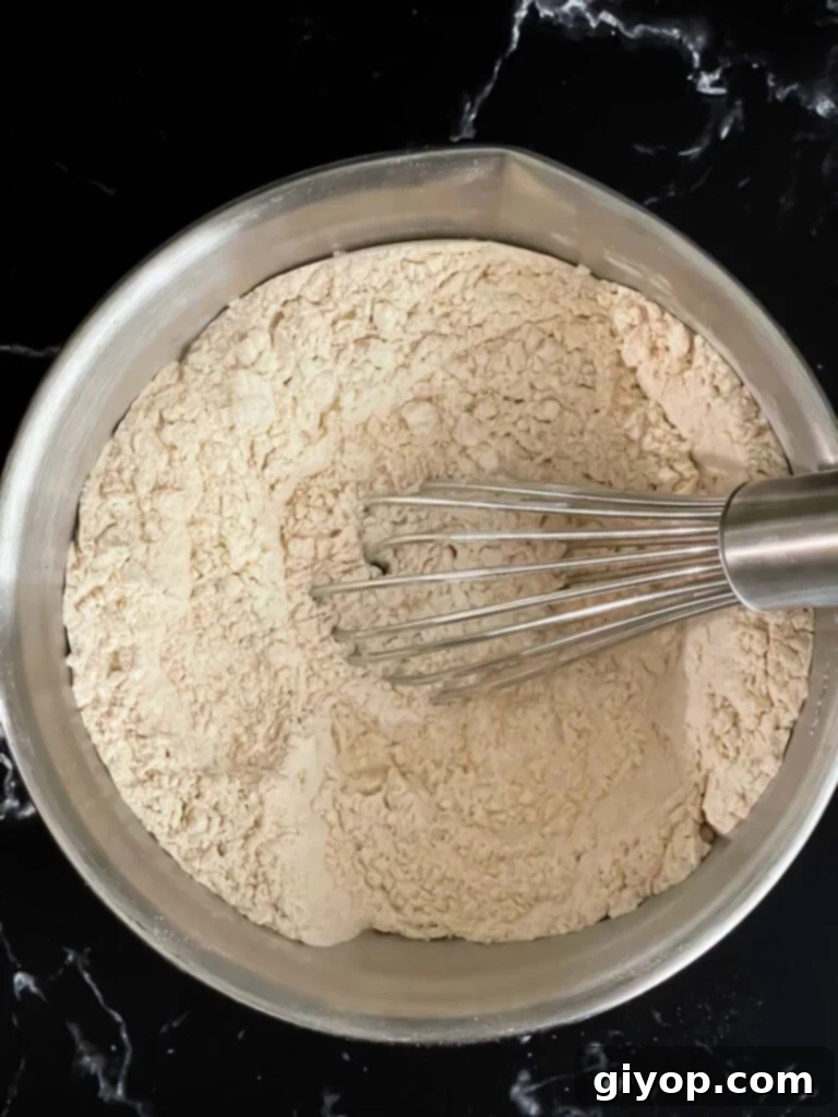 Dry ingredients like flour, spices, and baking powder are whisked together in a clean bowl, forming the base of the muffin batter.