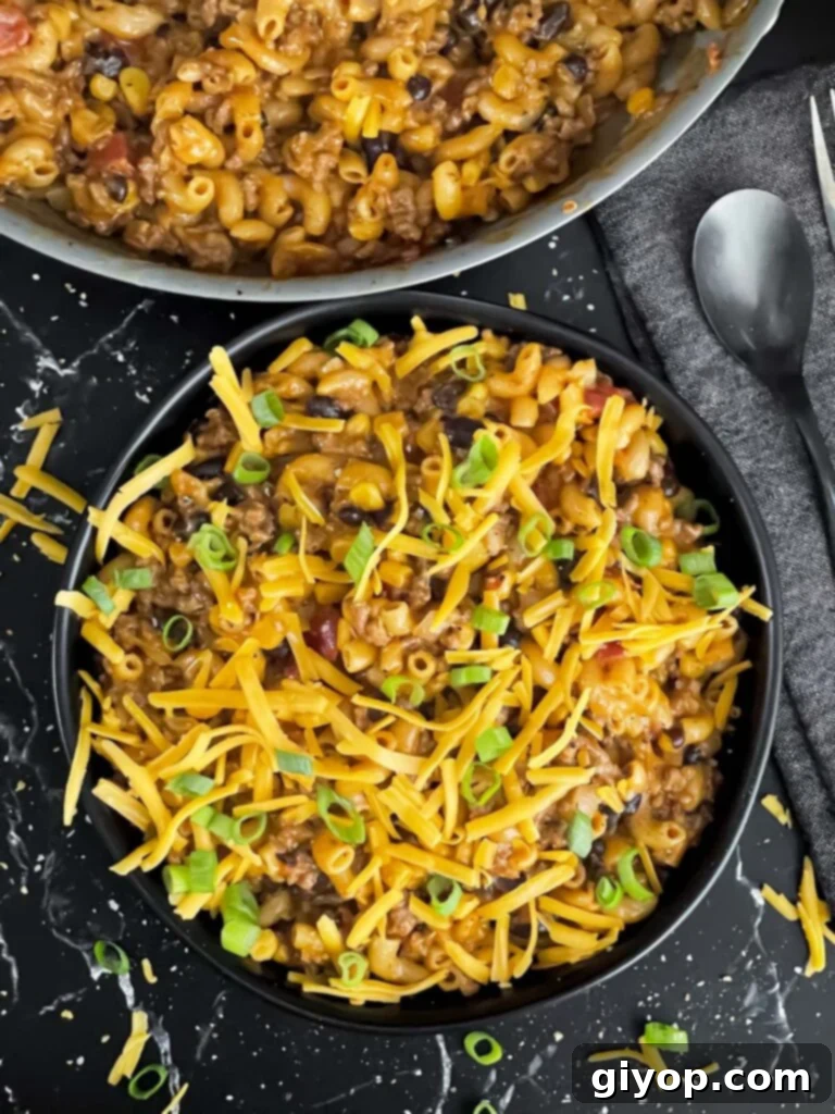 A serving of the delicious One-Pot Taco Pasta Skillet in a dark bowl, garnished and ready to eat.