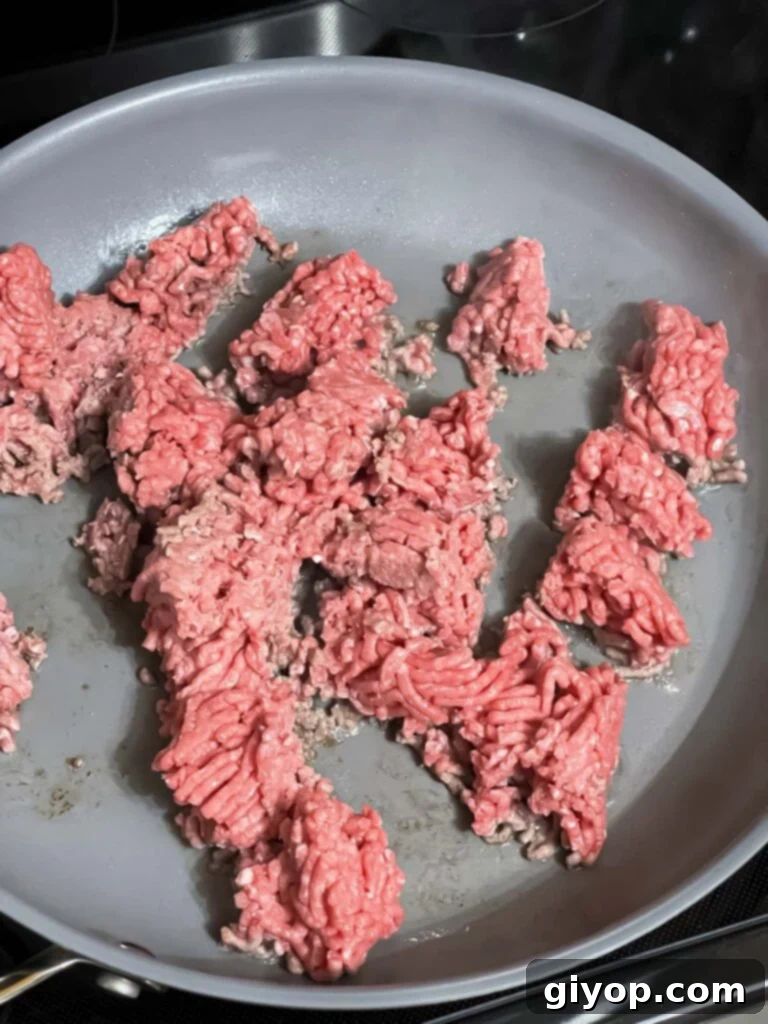 Ground beef browning in a large skillet over medium-high heat, forming the savory base for the taco pasta.
