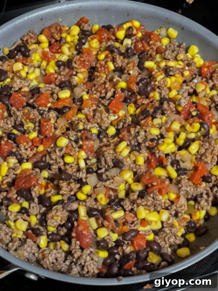 The taco pasta skillet simmering gently on the stovetop, with all ingredients combined and flavors melding.