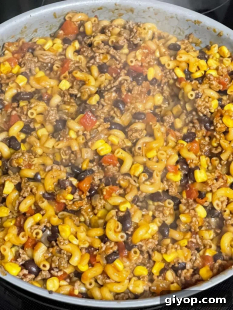 The one-pot taco pasta skillet actively cooking, with pasta absorbing the flavorful broth and sauce.