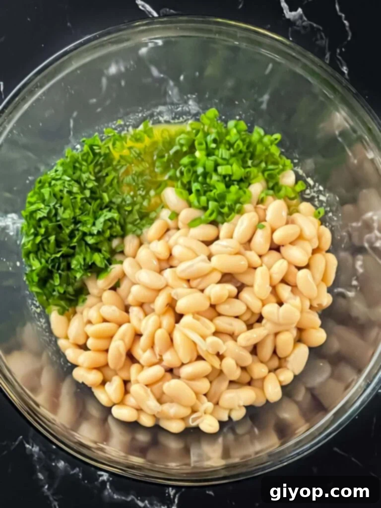 Bright Lemon White Bean Salad 6 White beans, green onions, and parsley added to the lemon dressing in a glass bowl, before mixing.