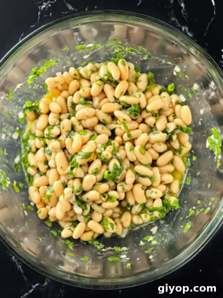 Bright Lemon White Bean Salad 7 The lemon white bean salad mixed thoroughly in a glass bowl, showcasing the vibrant colors and textures.