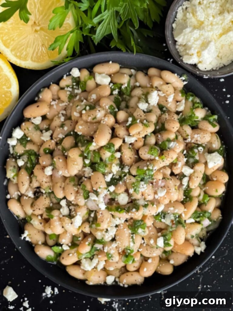 Bright Lemon White Bean Salad 8 A serving of Lemon White Bean Salad in a dark bowl, garnished with crumbled feta cheese.