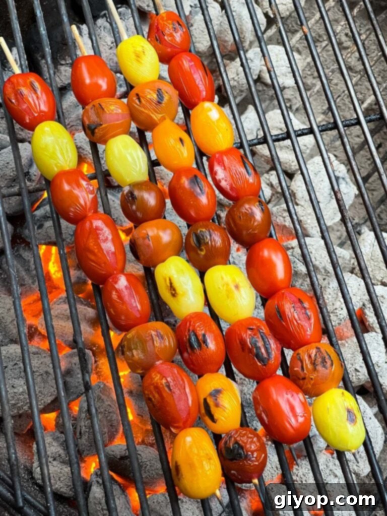 Grape tomatoes sizzling on the grill, starting to blister.