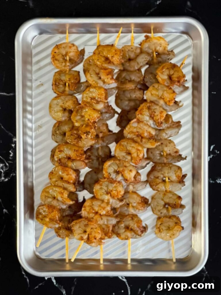 Close-up of raw seasoned shrimp on skewers, showing their vibrant color.