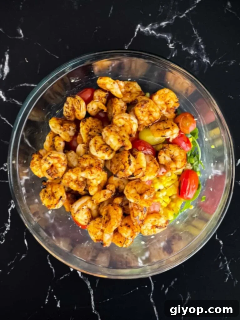 Grilled shrimp elegantly arranged on top of a fresh salad in a clear glass bowl.