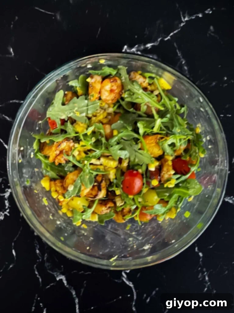 The finished grilled shrimp and corn salad in a clear glass bowl, showcasing its vibrant layers.