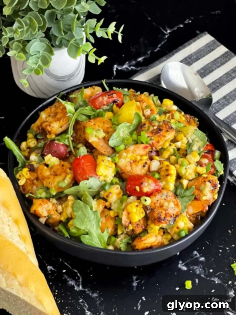 Two dark bowls filled with fresh grilled shrimp and corn salad, garnished with green onions.