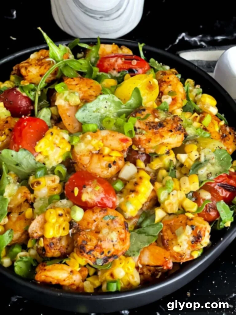 A close-up shot of grilled shrimp and corn salad in a dark bowl, emphasizing fresh ingredients.