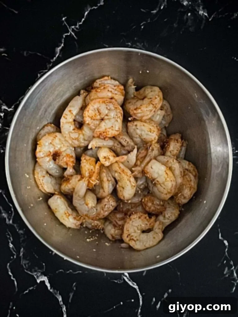 Seasoned raw shrimp glistening in a bowl, ready for skewering.