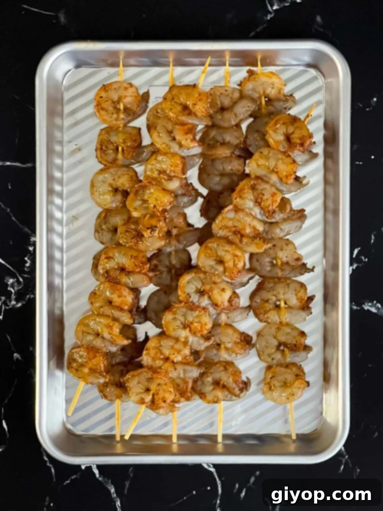 Raw, seasoned shrimp neatly arranged on wooden skewers.