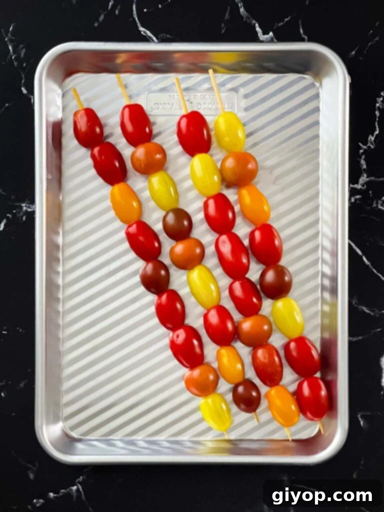 Bright red grape tomatoes threaded onto wooden skewers.