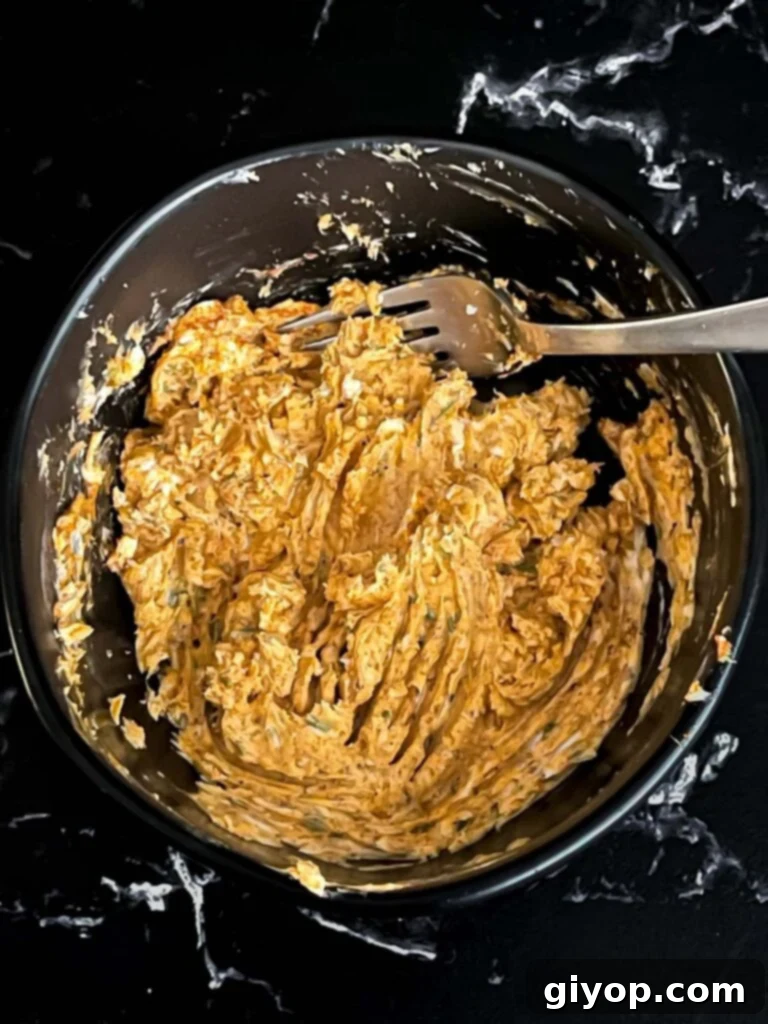 Lemon herb compound butter combined in a dark bowl on a dark surface.