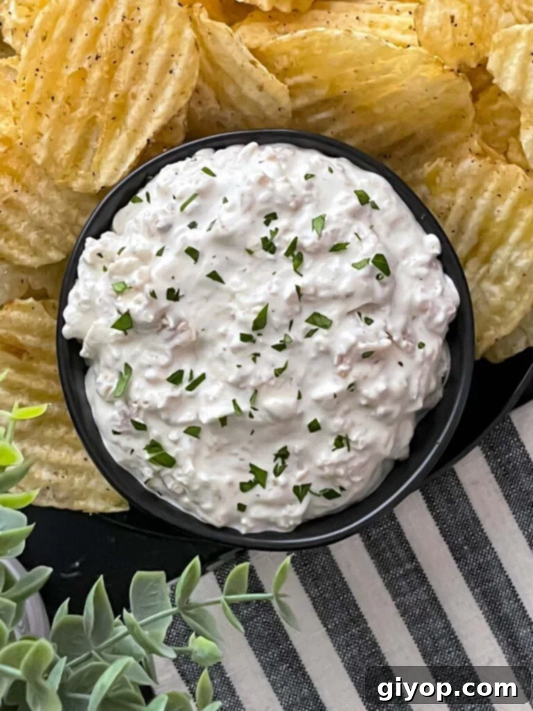 Chilled clam dip presented beautifully in a dark ceramic bowl, surrounded by a vibrant display of crunchy kettle potato chips, inviting a taste.