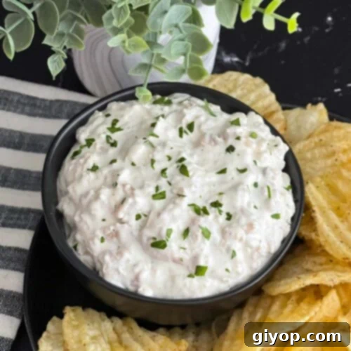 Clam dip in a dark bowl surrounded by kettle potato chips.