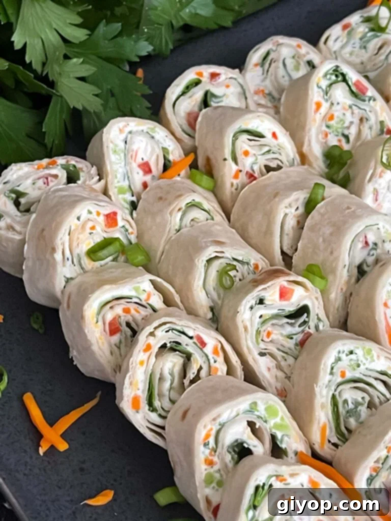 A serving of veggie tortilla roll ups lined up on a square dark plate, elegantly garnished with finely diced green onions and shredded carrots.