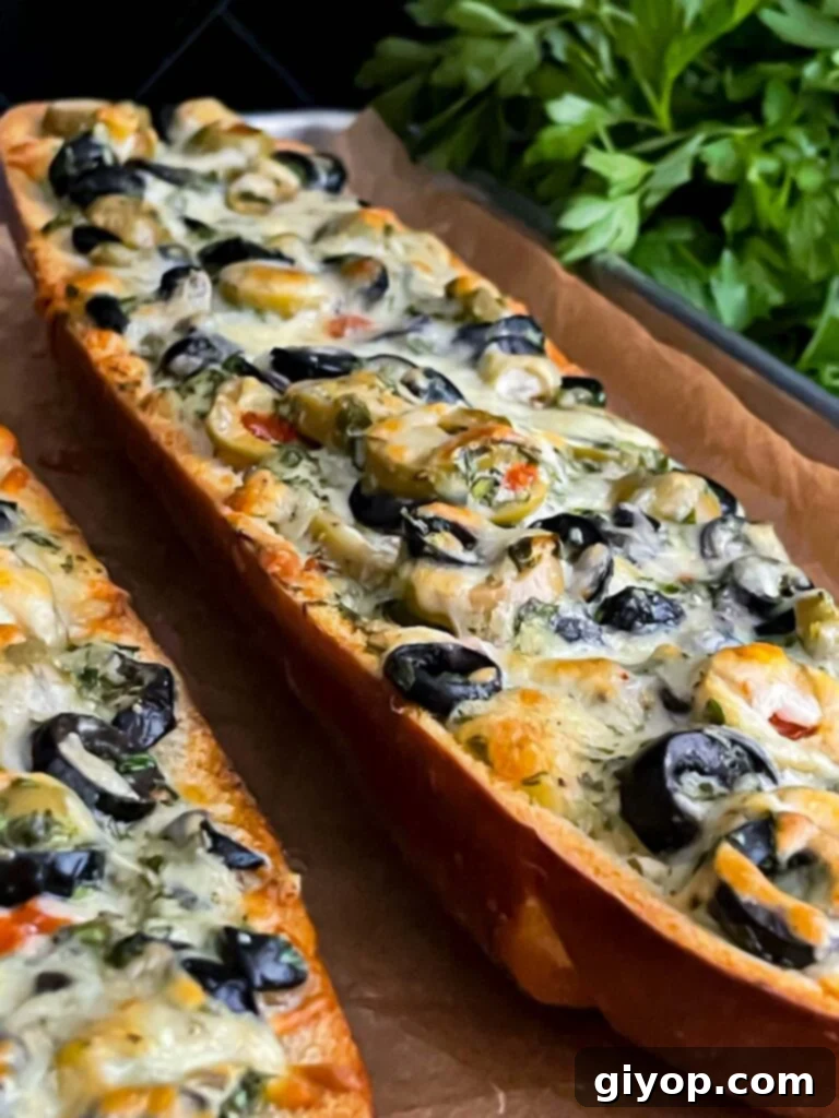 Baked olive cheese bread, hot and bubbly with melted golden cheese, cooling on a parchment paper lined baking sheet.