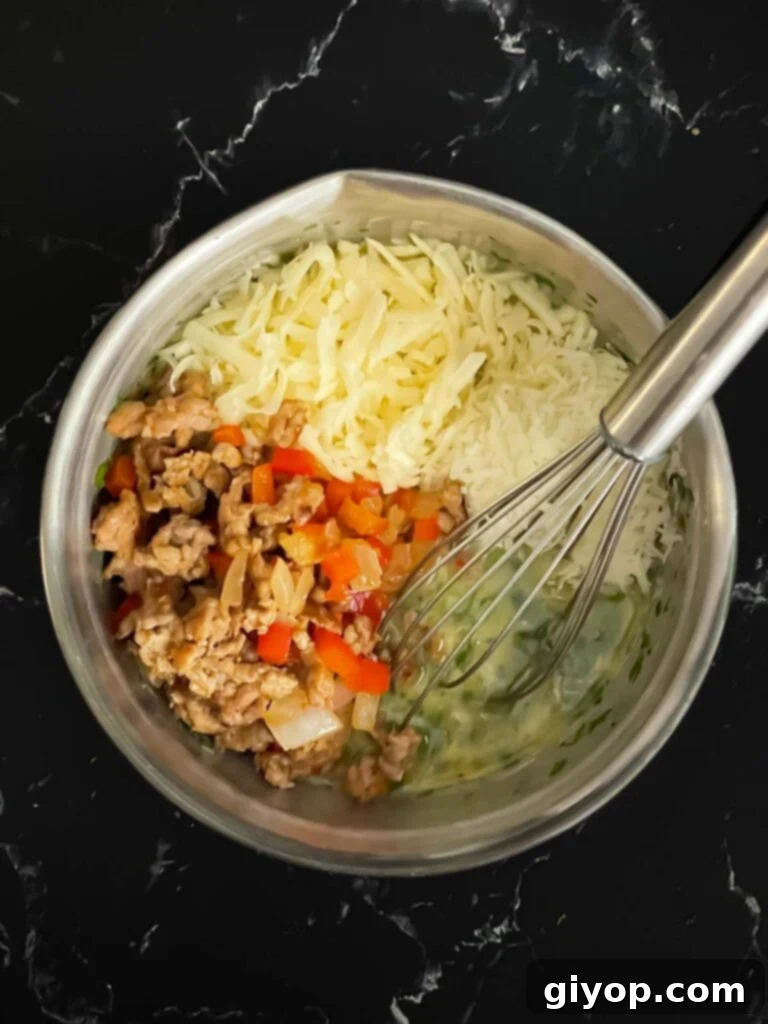 A large bowl containing whisked eggs, cream, herbs, and spices, ready for the sausage mixture.