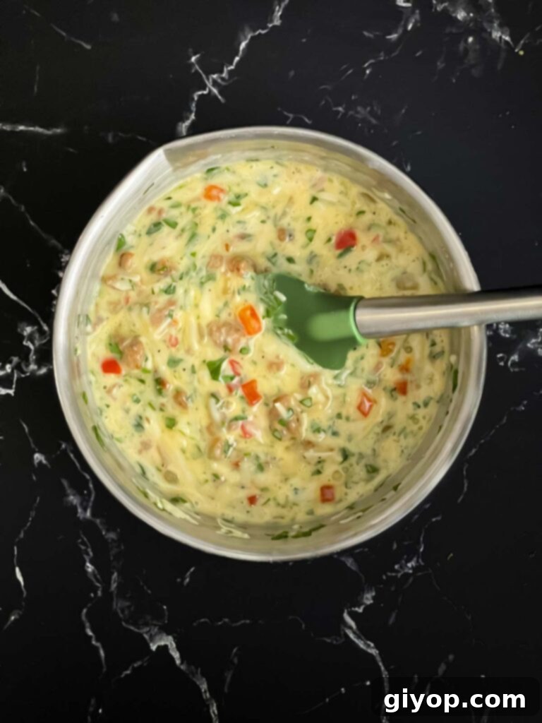 A well-combined mixture of eggs, sausage, vegetables, and cheeses in a bowl, ready for the baguette.