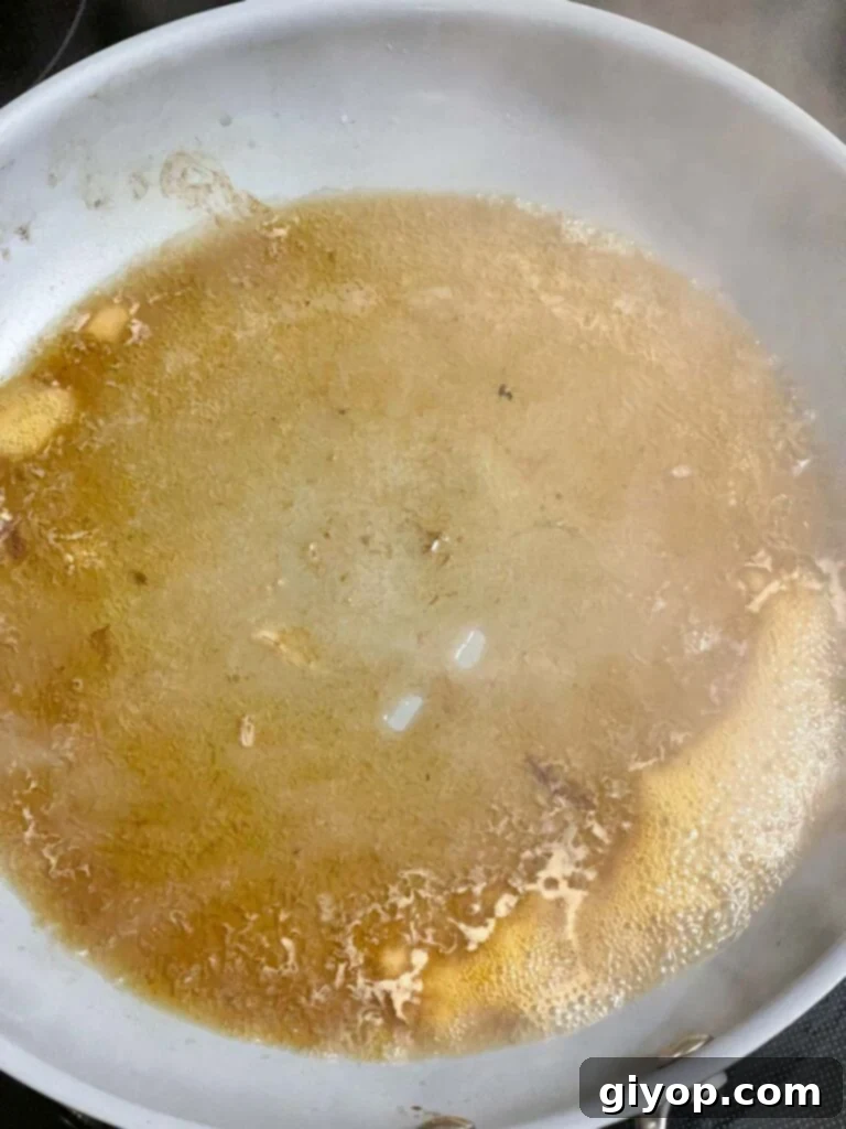 Beef broth added to a hot skillet to deglaze, scraping up flavorful browned bits.