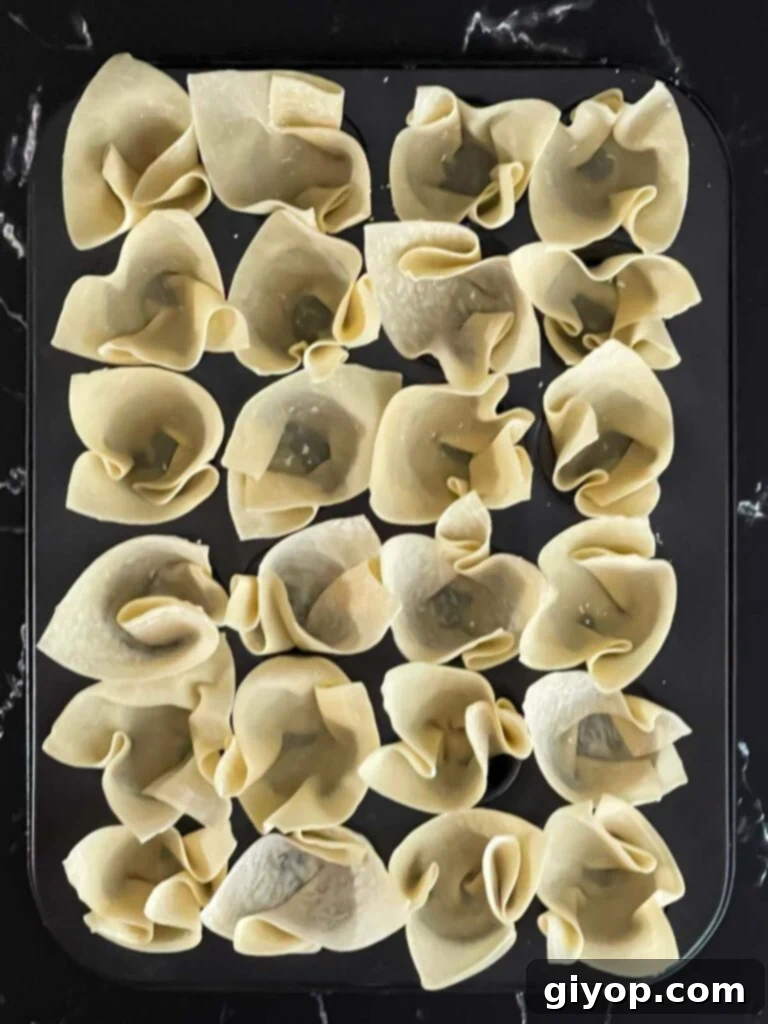 Wontons carefully placed in a mini muffin pan, ready for their first bake.