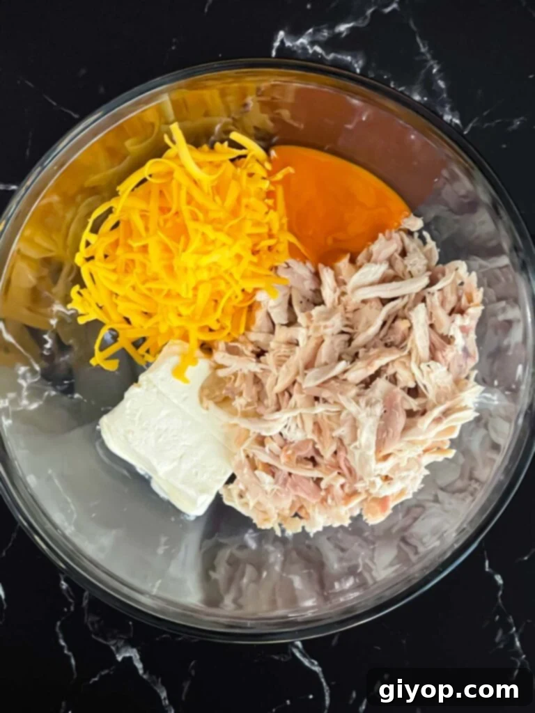 All ingredients for the buffalo chicken filling measured out in a glass bowl.